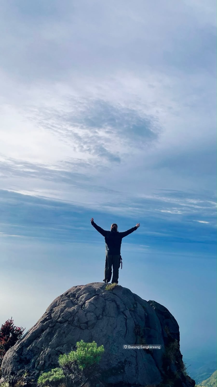 Hiker on the summit rock of Sangkareang mountain, Lombok